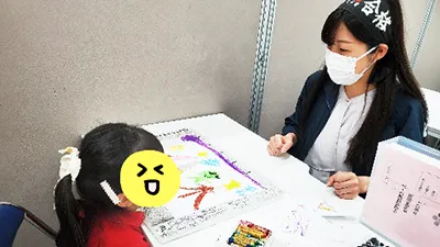 年長クラスのカリキュラムで課題を講師に採点してもらっているシーン