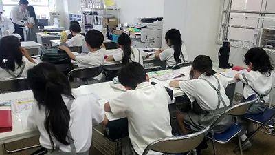 小学生1年生と小学校2年生用のカリキュラムのワンシーンで生徒と講師が受験合格という目的に向かって学習に取り組んでいるシーン
