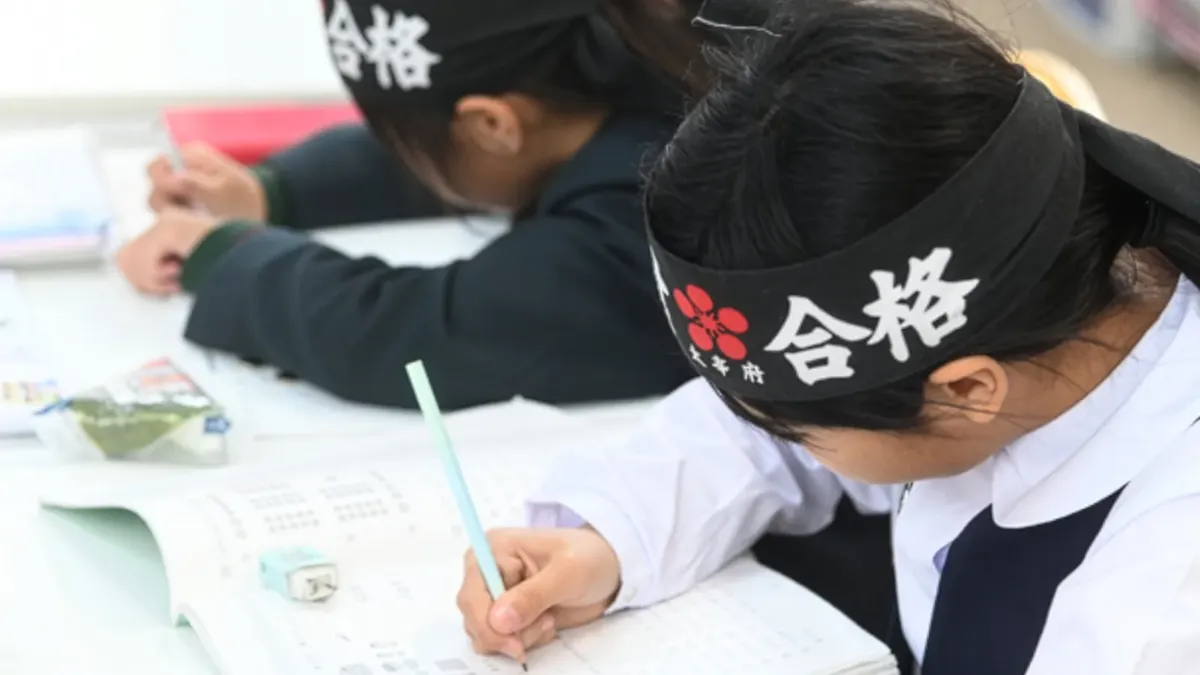 小学生の生徒が熱心に受験に向けて問題を解いているシーン