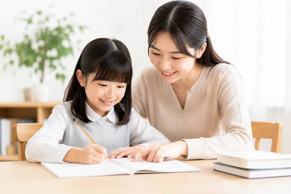 保護者と小学生の生徒が自宅でテスト勉強をしているシーン